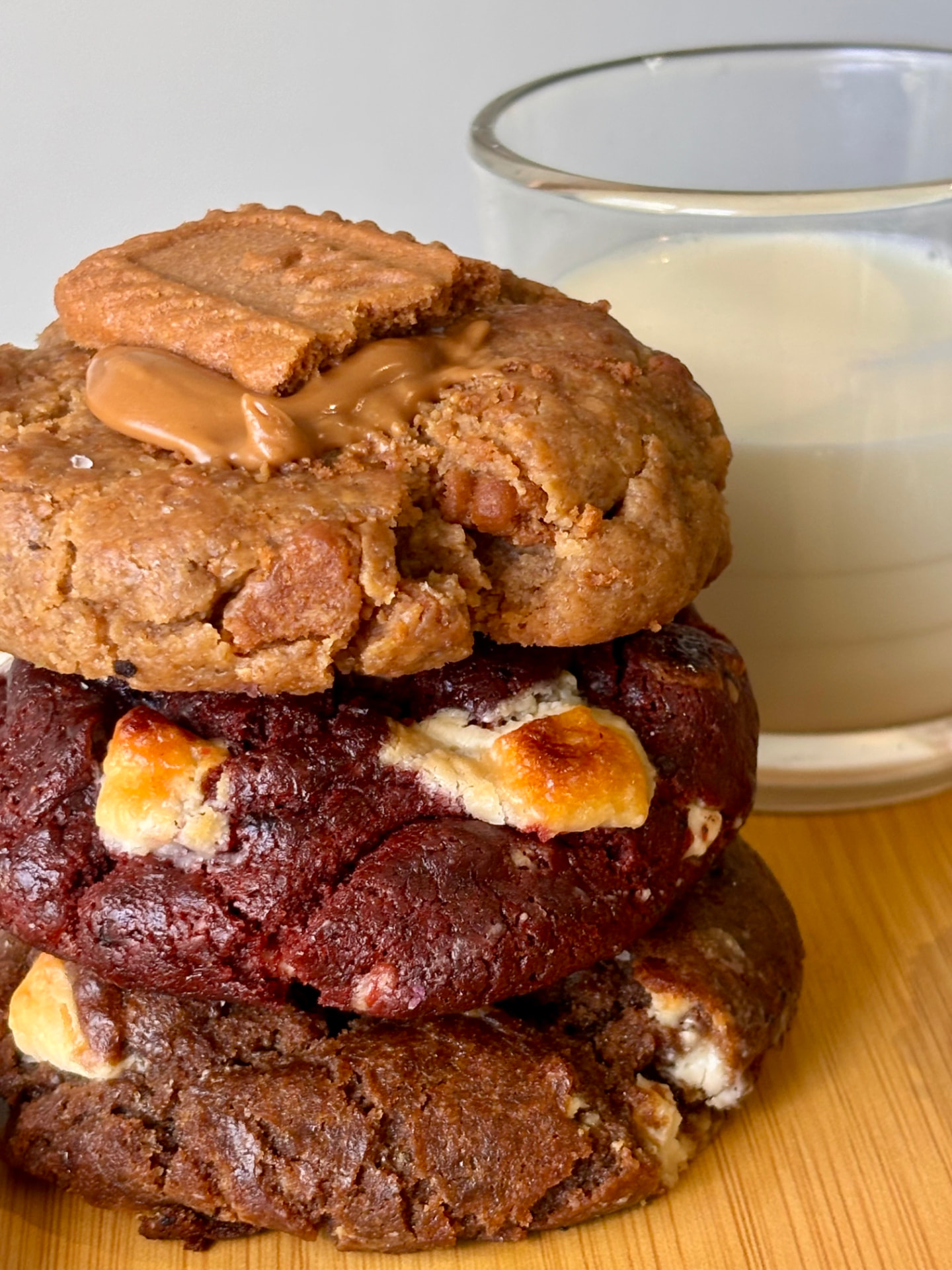 Stack of Hana Kumi cookies — Campfire Kiss, red velvet and cookies & cream — beside a glass of milk